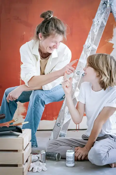 A mom and son take a break from painting a room.