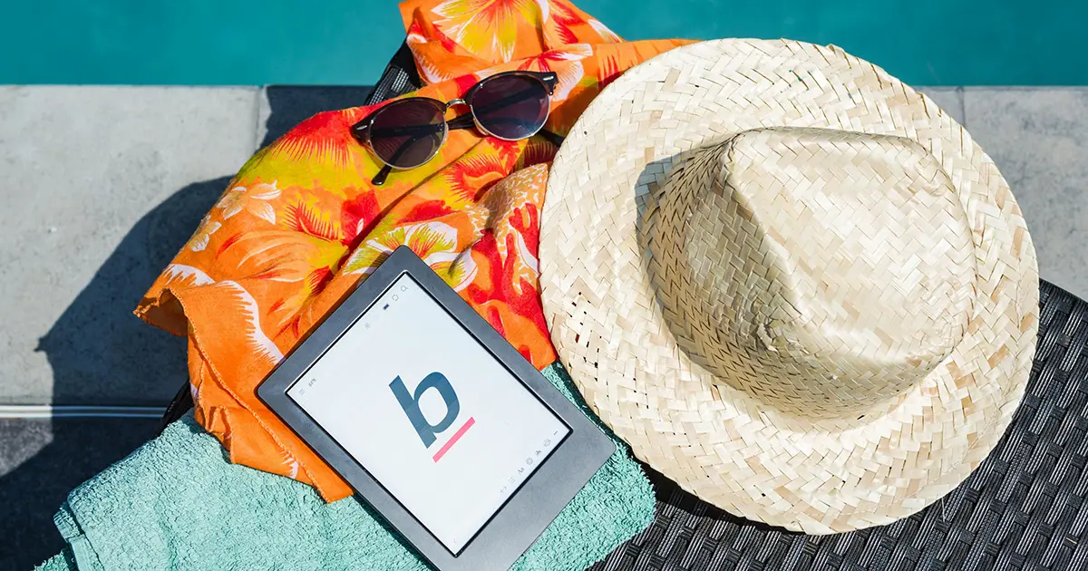 A sunhat, sunglasses, and a reading tablet poolside during summer.