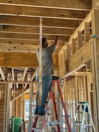 Evan is on the main floor securing ductwork above.